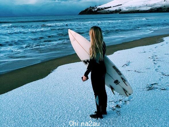 A teenage girl looks out over the water from a snow-covered beach south of Hobart in 2015