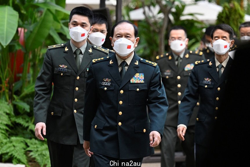 Wei Fenghe and other members of the Chinese delegation walk in military uniform and face masks.