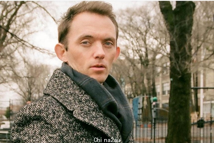 Mark Dessaix looks at the camera in Central Park wearing a winter coat. 