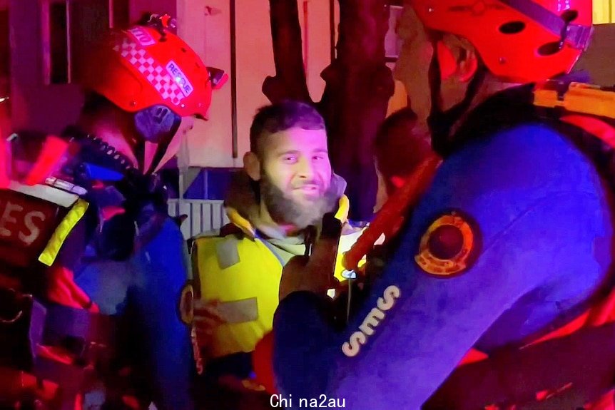 A man smiles at a camera with SES officers around him 