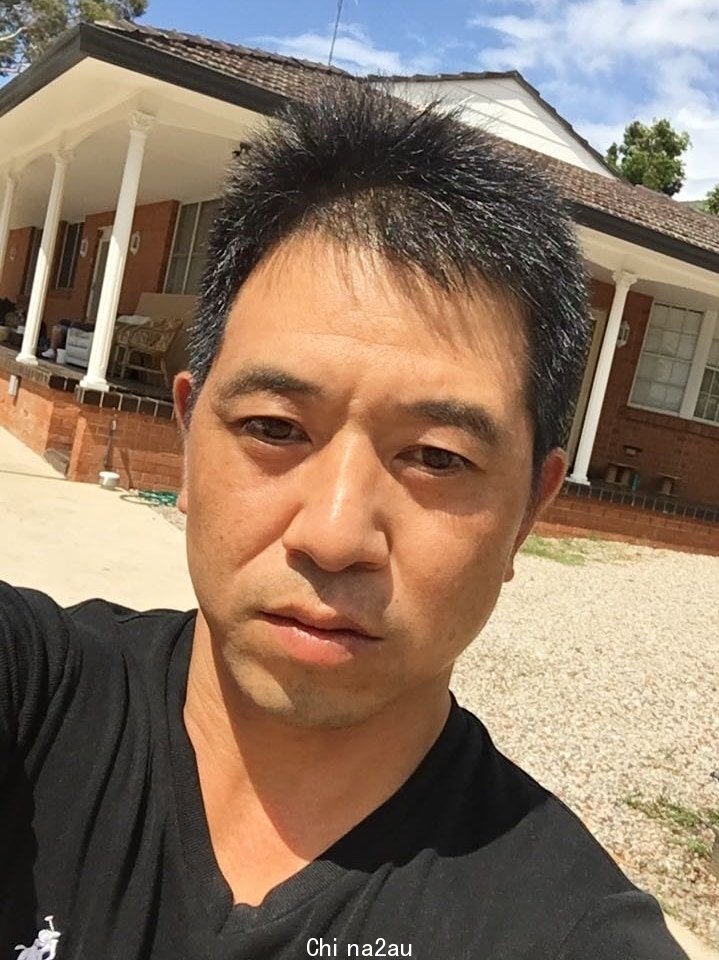 A man stands in front of a house.