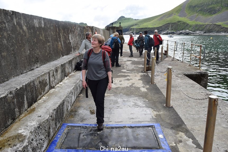 Woman casually walks across padded mad on footpath