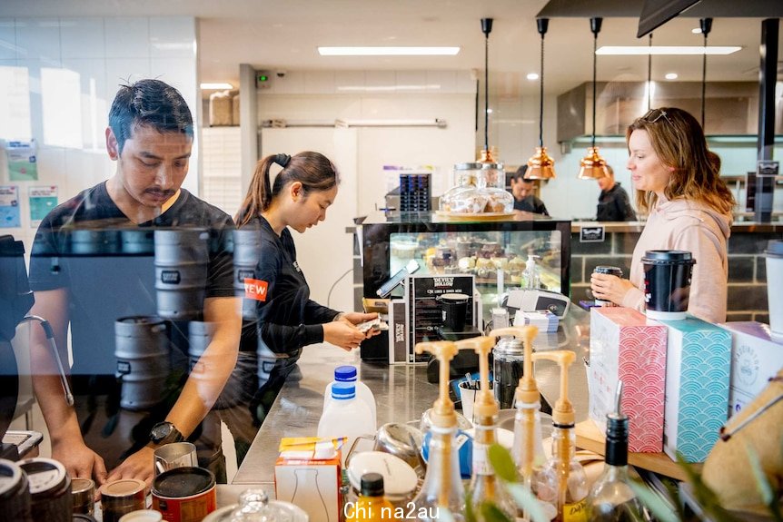 Two people working at a cafe and a customer