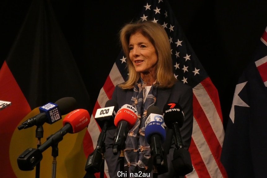 Caroline Kennedy speaks at a press conference in front of US, Australian and Aboriginal flags