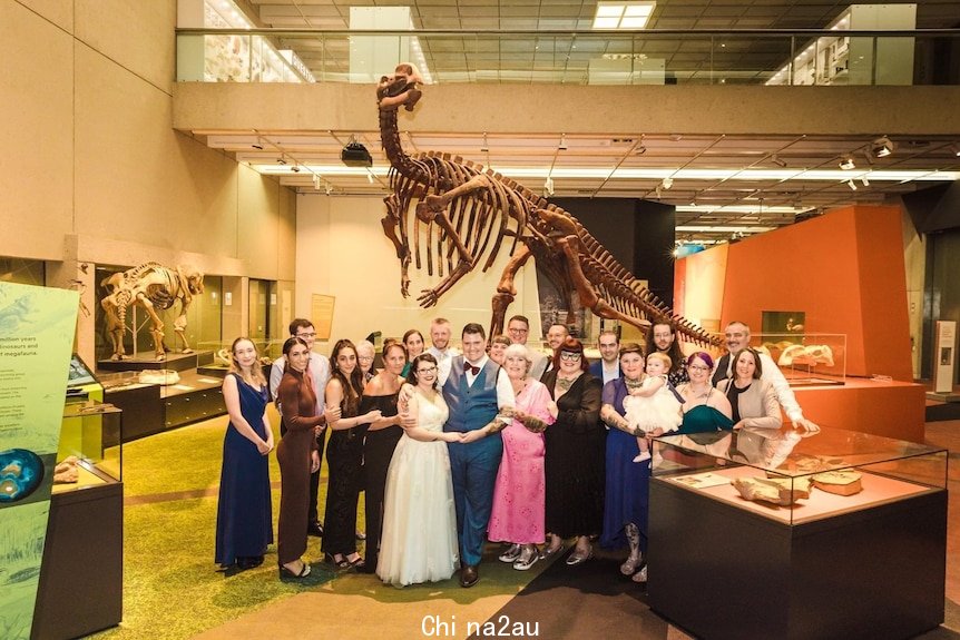 Couple standing with family under a dinosaur skeleton