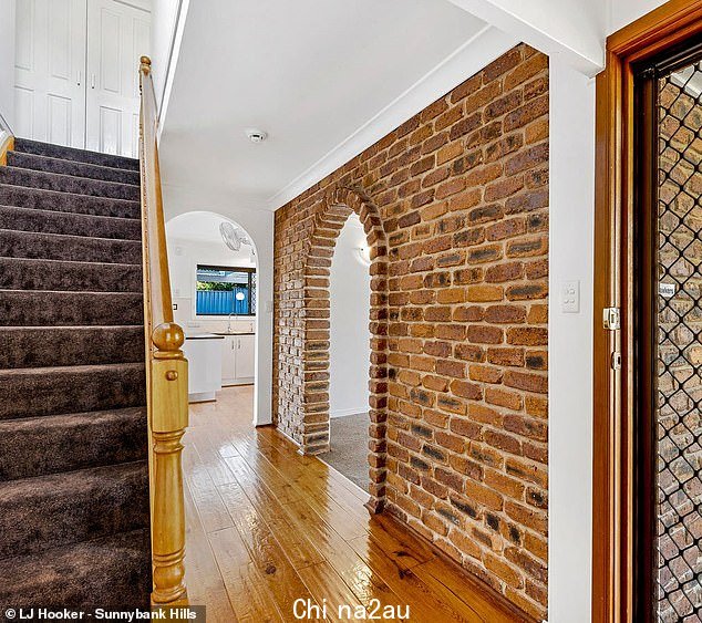 A stylish brick archway at the home sits in-between a large living room and the main hallway
