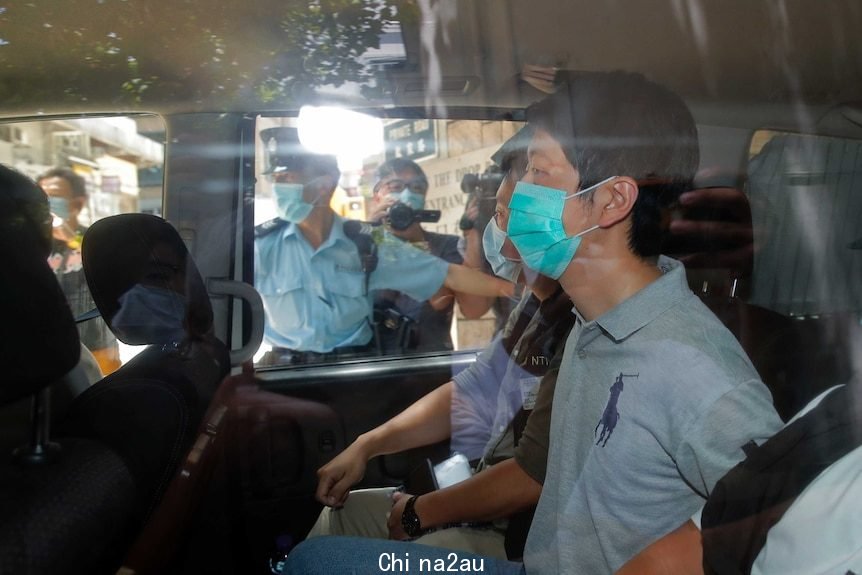 Pro-democracy legislator Ted Hui sits in a car with police wearing a face mask.