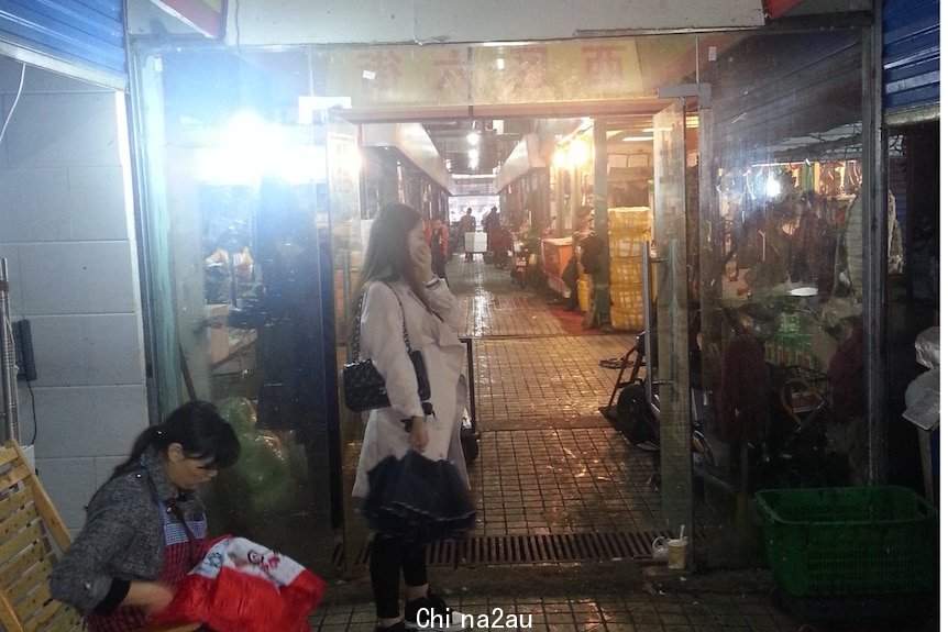 Dark and dirty entrance to a market with signs in Chinese.