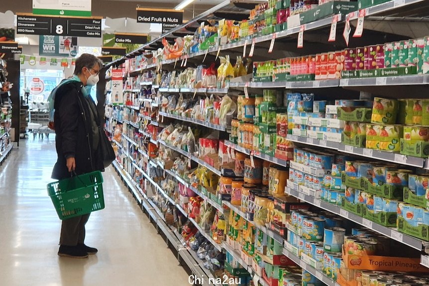 Woman in mask shopping in Woolworths packaged food aisle June 28