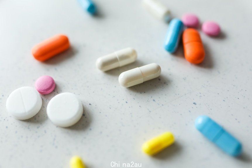 Vitamins in different shapes and bright colours scattered across a white bench