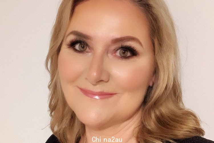 A headshot of a woman with curled blonde hair, smiling and looking at the camera with a white background