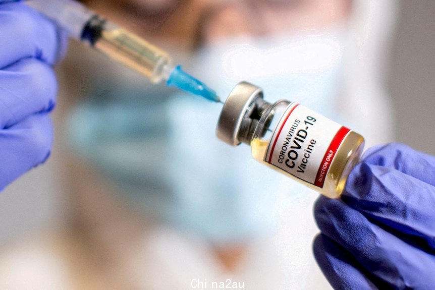 A woman holds a medical syringe and a small bottle labelled 