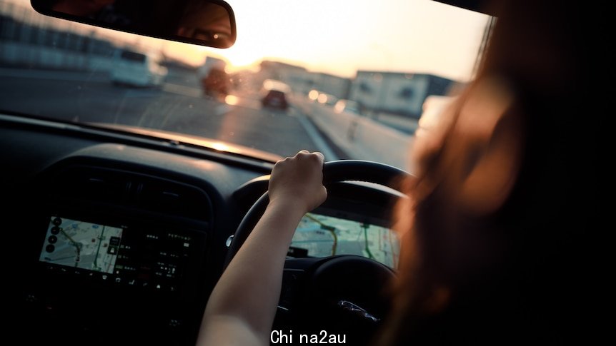 Woman driving a car, urban road in front of her