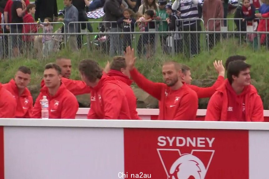 Sydney Swans players wave to fans from a barge on the Yarra River during the 2022 grand final parade.