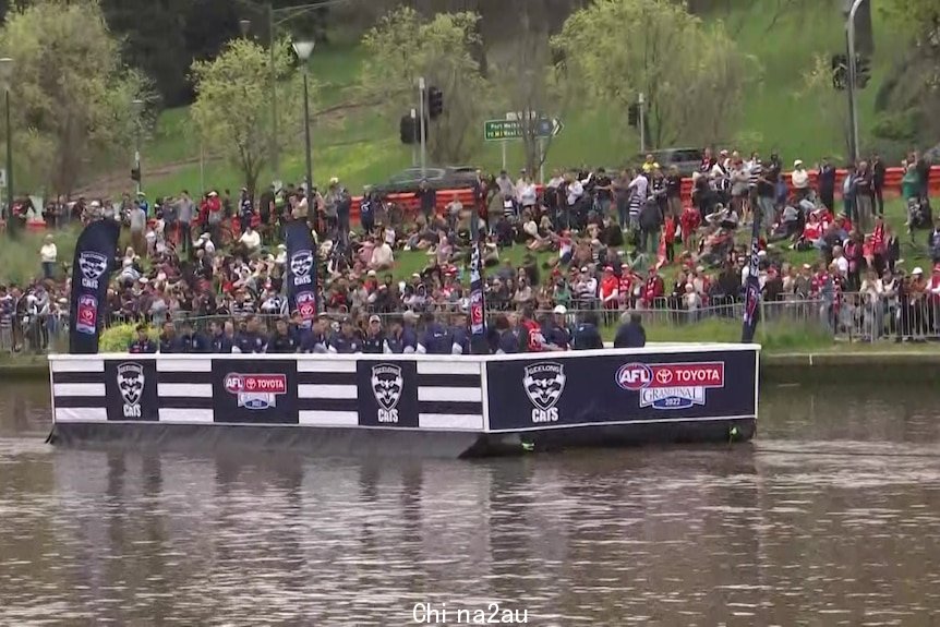The Geelong Cats sail down the Yarra River in a Cats branded barge