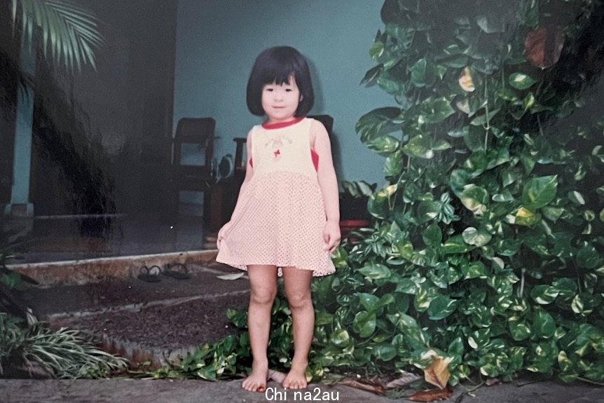 A three-year-old Chinese Indonesian girl standing in front of a house.