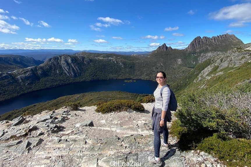 Woman wearing glasses standing on a mountain.