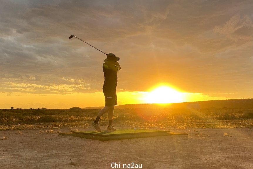 Golfer hitting a ball in front of a setting sun.