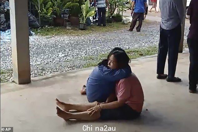 一个悲痛欲绝的女人在地板上得到安慰血洗后的托儿所外