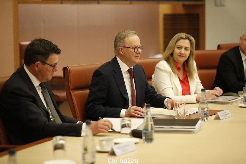 Andrews, Albanese and Palaszczuk sit at a long table with some papers talking, with others out of frame.