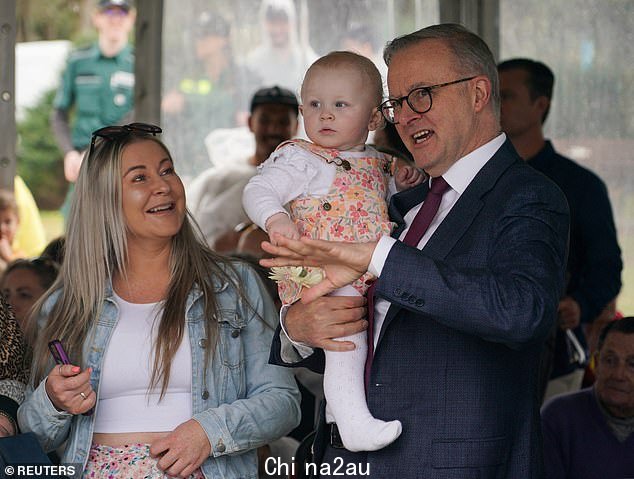 澳大利亚总理 Anthony Albanese 在纪念巴厘岛爆炸案 20 周年的追悼会上与受害者家属交谈时抱着 1 岁的 Capria Thompson