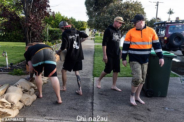 来自维多利亚州北部被洪水蹂躏的 Shepparton 镇的图像显示,居民们在齐膝高的泥水中涉水穿过被蹂躏的小镇并准备沙袋