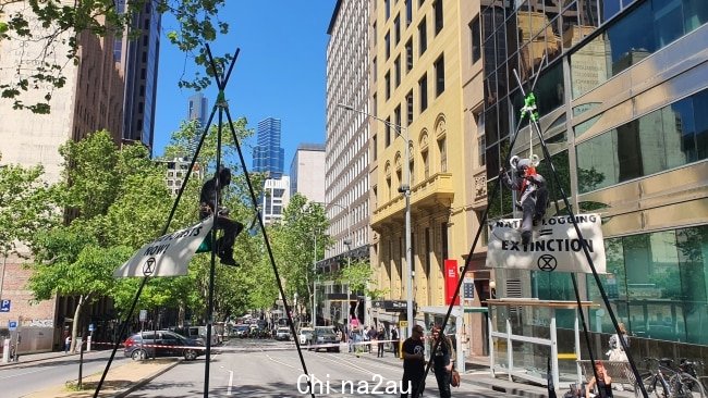 灭绝叛乱抗议者悬挂在三脚架上以抗议森林砍伐。图片：先驱太阳报，Mitch Ryan