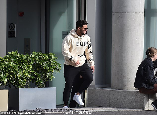 忙碌:离开家后,他穿着一件 Burberry 连帽衫,戴着耳机北部城市的豪华公寓楼