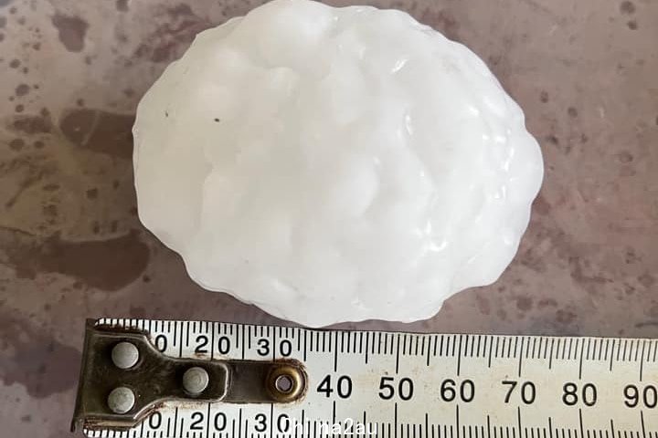 A large hail stone next to a ruler