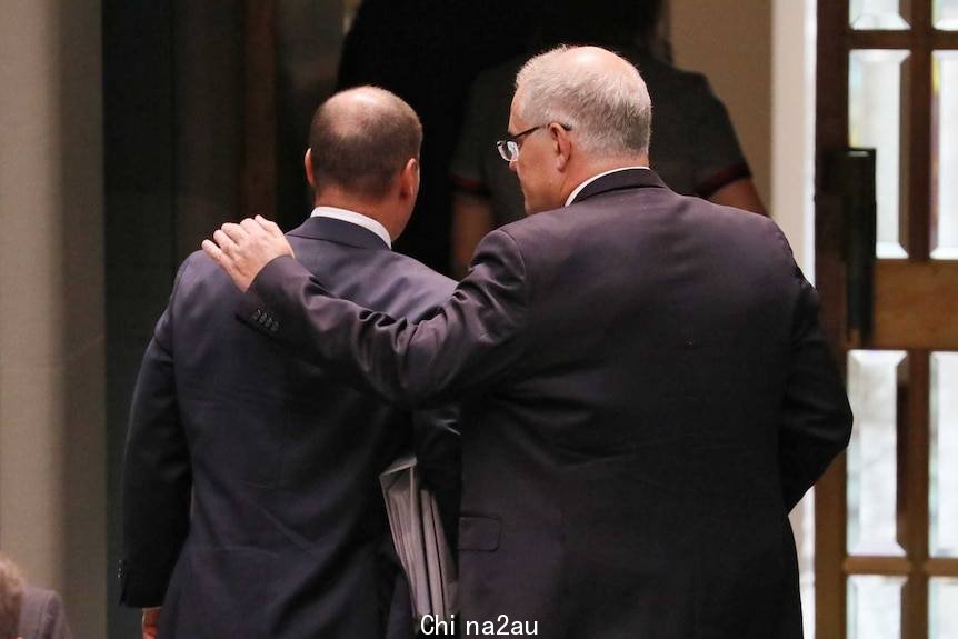 Prime Minister Scott Morrison is seen from behind putting his arm around Treasurer Josh Frydenberg as they leave Parliament.