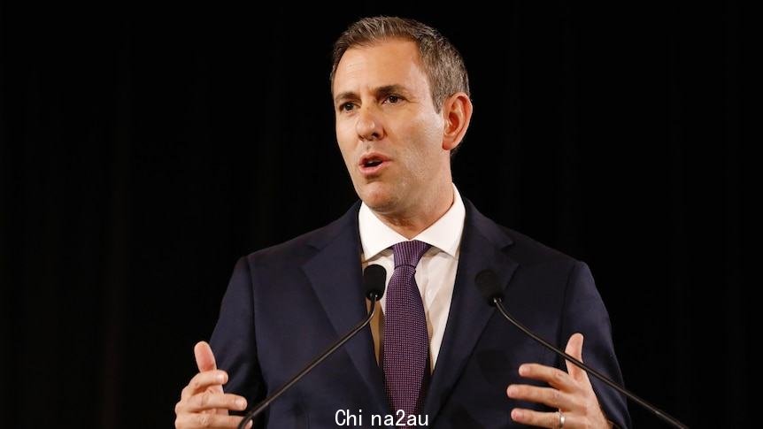 Chalmers gestures with both hands while standing in front of a lectern.