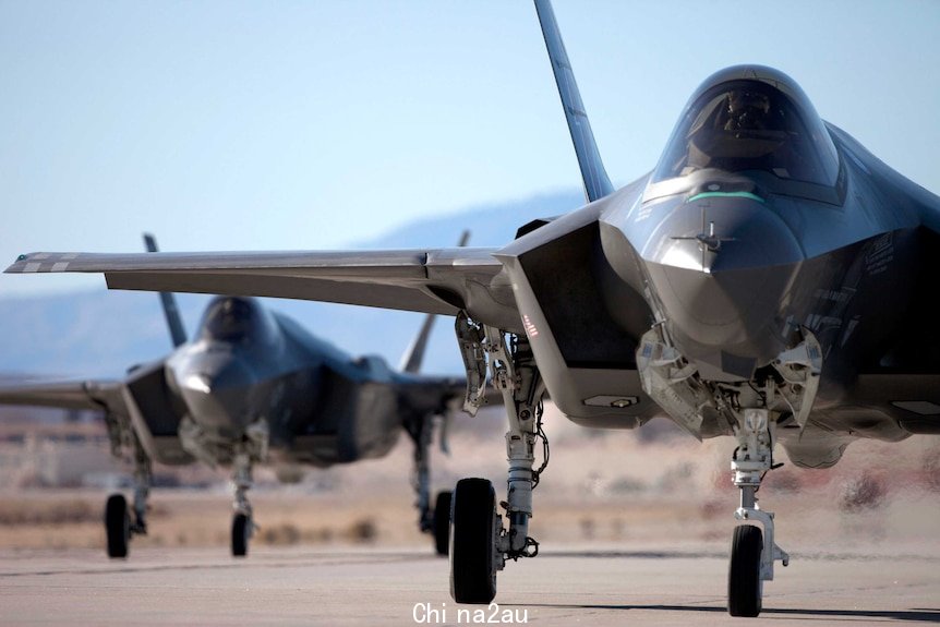 Dark military aircrafts viewed head-on on a runway