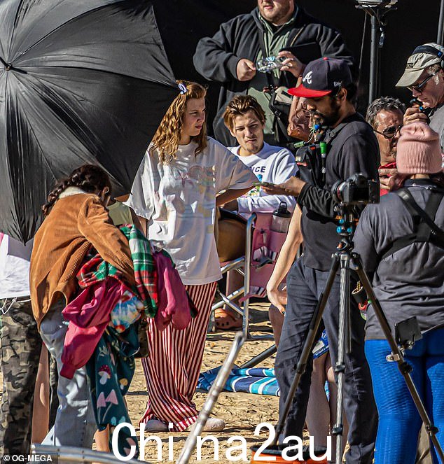 Ac化!两届艾美奖提名人米莉·鲍比·布朗 (Millie Bobby Brown) (2-L) 周三继续在佐治亚州的海滩上拍摄 Netflix 的 The Electric State,很可能是泰碧岛,因为她的男友 Jake Bongiovi (M) 观看了“class=