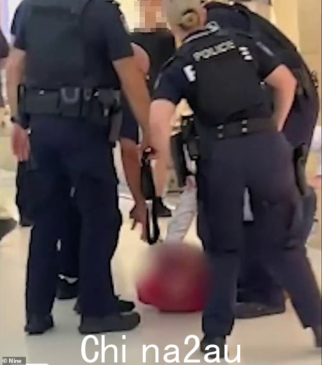 当警察介入帮助时,可以听到男孩尖叫(如图),吓坏了的购物者看着