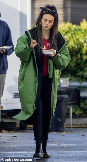 包装d up:这位美女在大衣下穿上一件醒目的红色套头衫和黑色紧身牛仔裤,在她走出拖车时摇晃着一双系带靴子