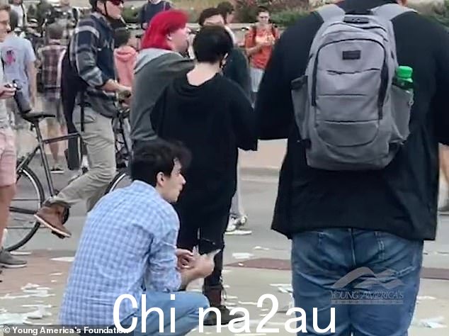 可以看到红发的抗议者将基督教圣书的几页塞进她的嘴里,学生们在后台嘲笑和欢呼