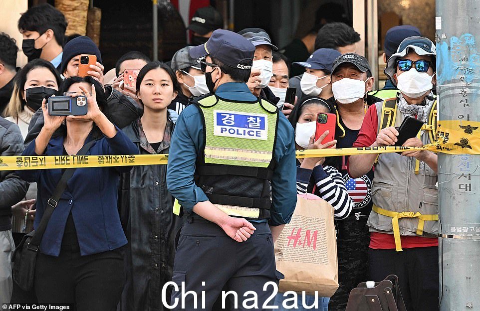 大批人群聚集在现场周围的警戒线上,查看发生万圣节踩踏事件的街道