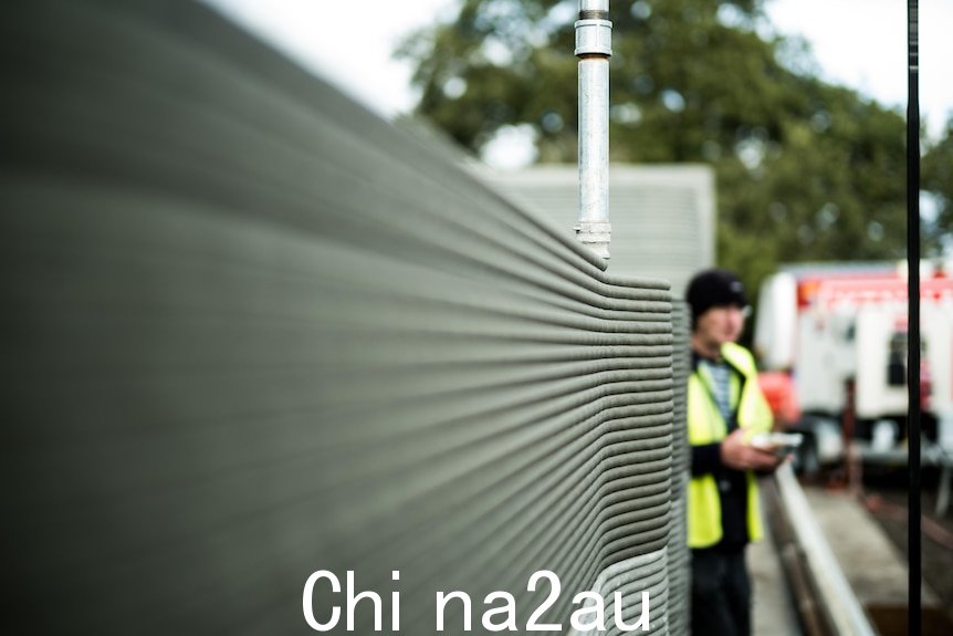 A man inspects a 3D printed wall.