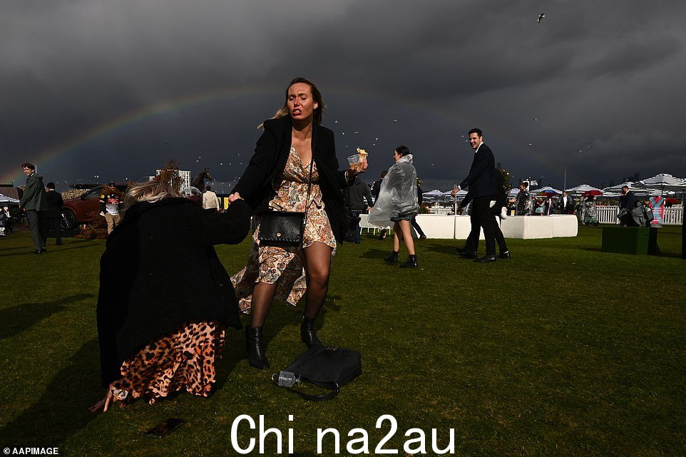 一位女士向她的朋友伸出了援助之手,因为无意中听到暴风雨的形成,赛马者离开了弗莱明顿赛马场