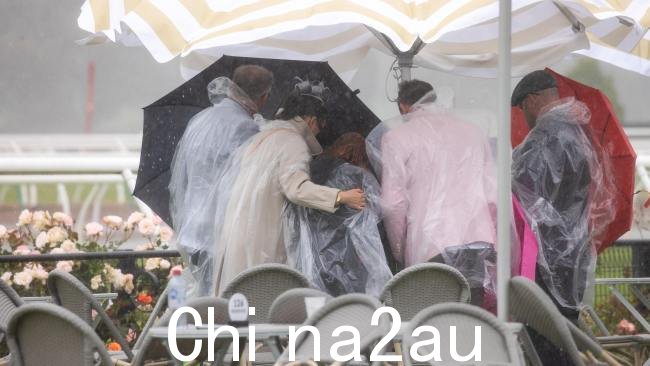 Melbourne Cup周二下午,与会者试图在弗莱明顿赛马场避雨。图片:Jason Edwards