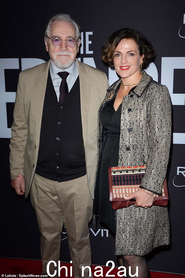 Dapper: Brian Cox 身着米色西装,搭配蓝色衬衫和黑色背心,与妻子 Nicole Ansari 合影留念img-share
