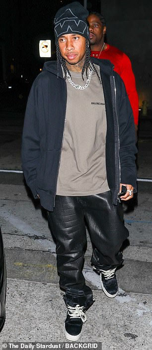 休闲:他穿着黑色乙烯基裤子搭配深色夹克和灰色 Balenciaga T 恤