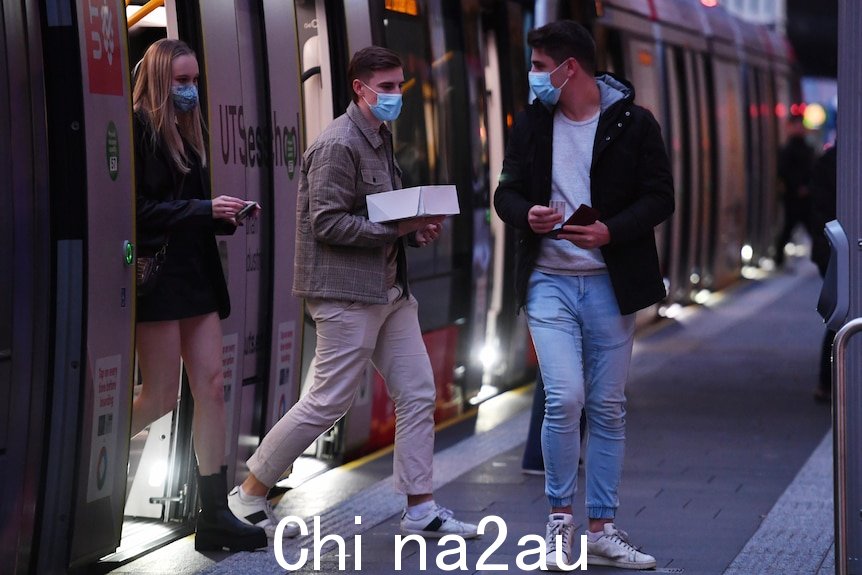 a group of young people hopping off a tram wearing face masks