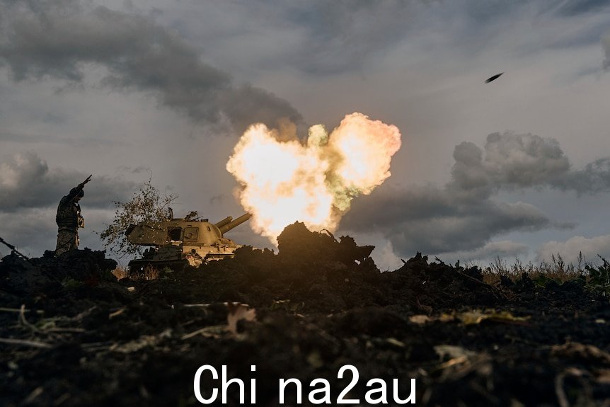 A Ukrainian serviceman reacts as a self-propelled artillery vehicle fires.