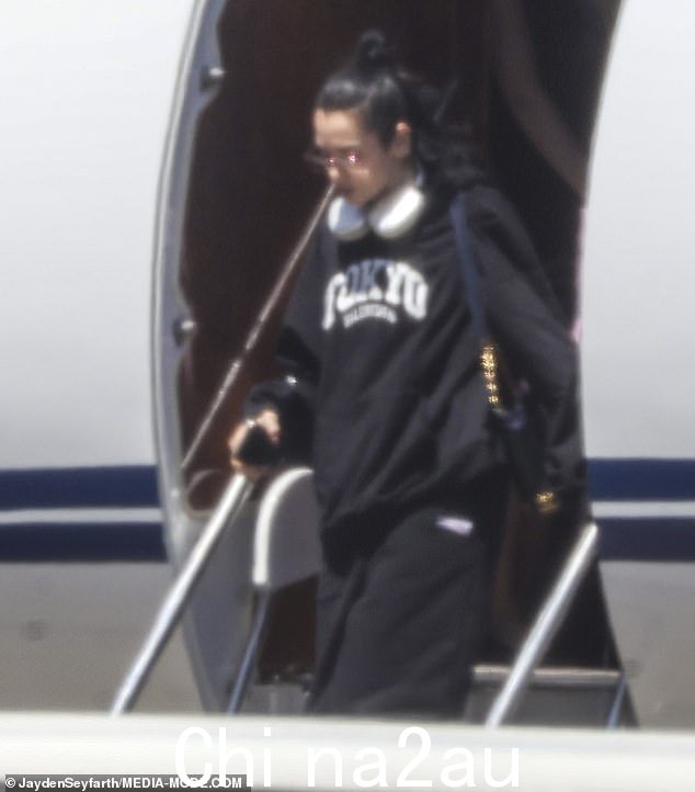这位流行歌星穿着时尚的黑色东京套头衫和运动裤,一身时尚休闲装