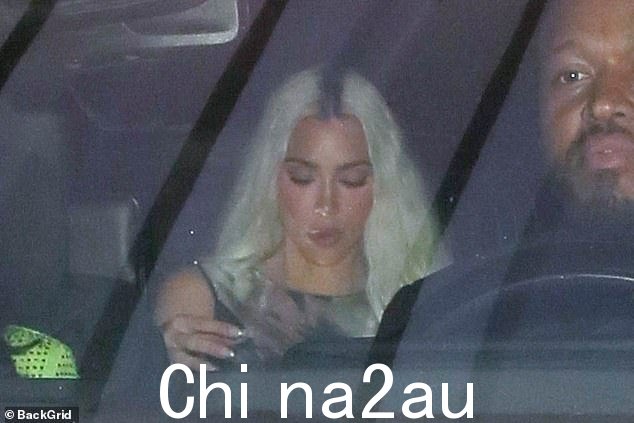 盯着她的手机看:卡戴珊的明星金·卡戴珊(Kim Kardashian)——她的妹妹科勒(Khloé)和特里斯坦(Tristan)生了两个孩子——被发现开着她的车来到贝克汉姆的狂欢节