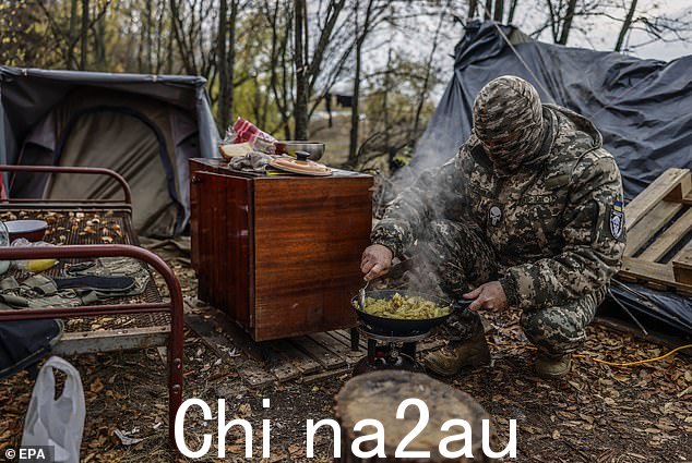 周六,一名乌克兰士兵在赫尔松地区北部的一个阵地准备食物