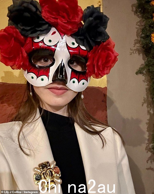 亡灵节:Lily 以红黑相间的 dia de Los Muertos 面具与周围的黑红玫瑰保持万圣节精神the top