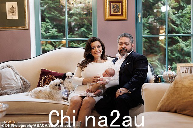 新的父母是当他们可爱的狗坐在他们旁边与新生儿合影时,他们为相机而高兴” class=