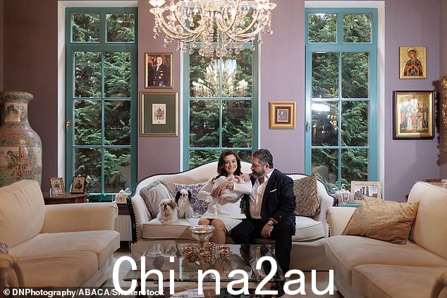两人在奶油色沙发上摆姿势,旁边是被华丽家具包围的可爱小狗